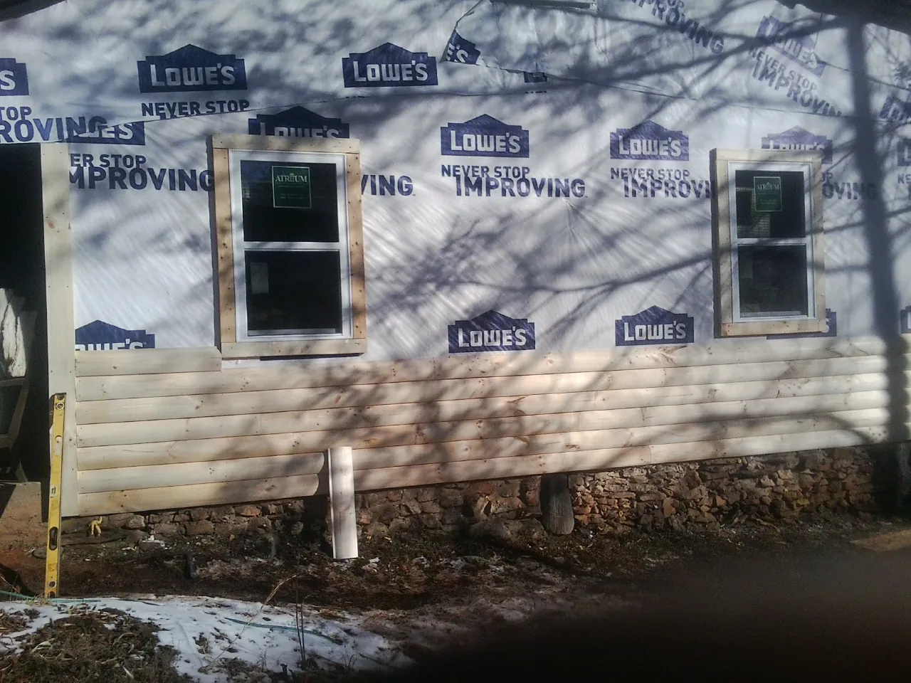 House wrap and new log siding going up on an exterior wall in Castle Rock