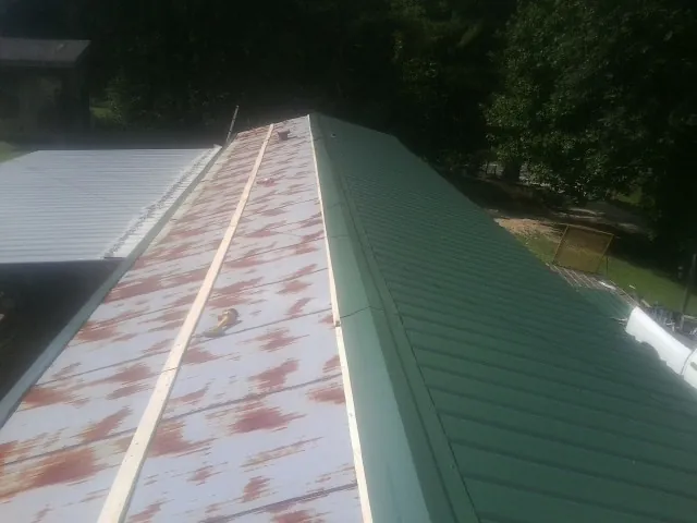 Old rusted panels beside newly installed green metal roofing — Wind Damage Roof Repair by Roofing Brothers in Castle Rock