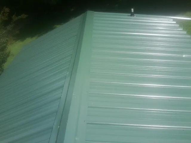 New green metal panels meeting at the ridge of a roof — Flat Roof Repair work by our crew in Castle Rock
